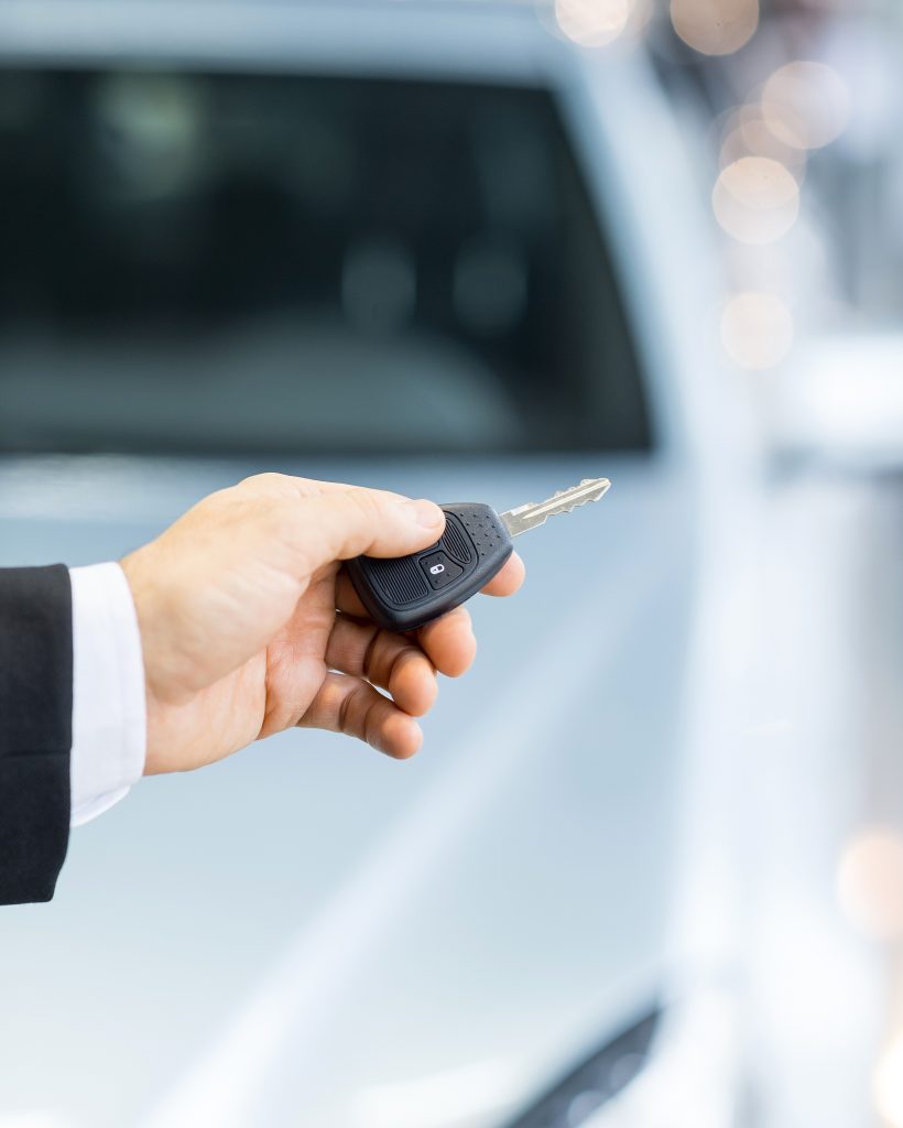 Drive carefully! Close up shoot of the hand holding car keys in front of a car