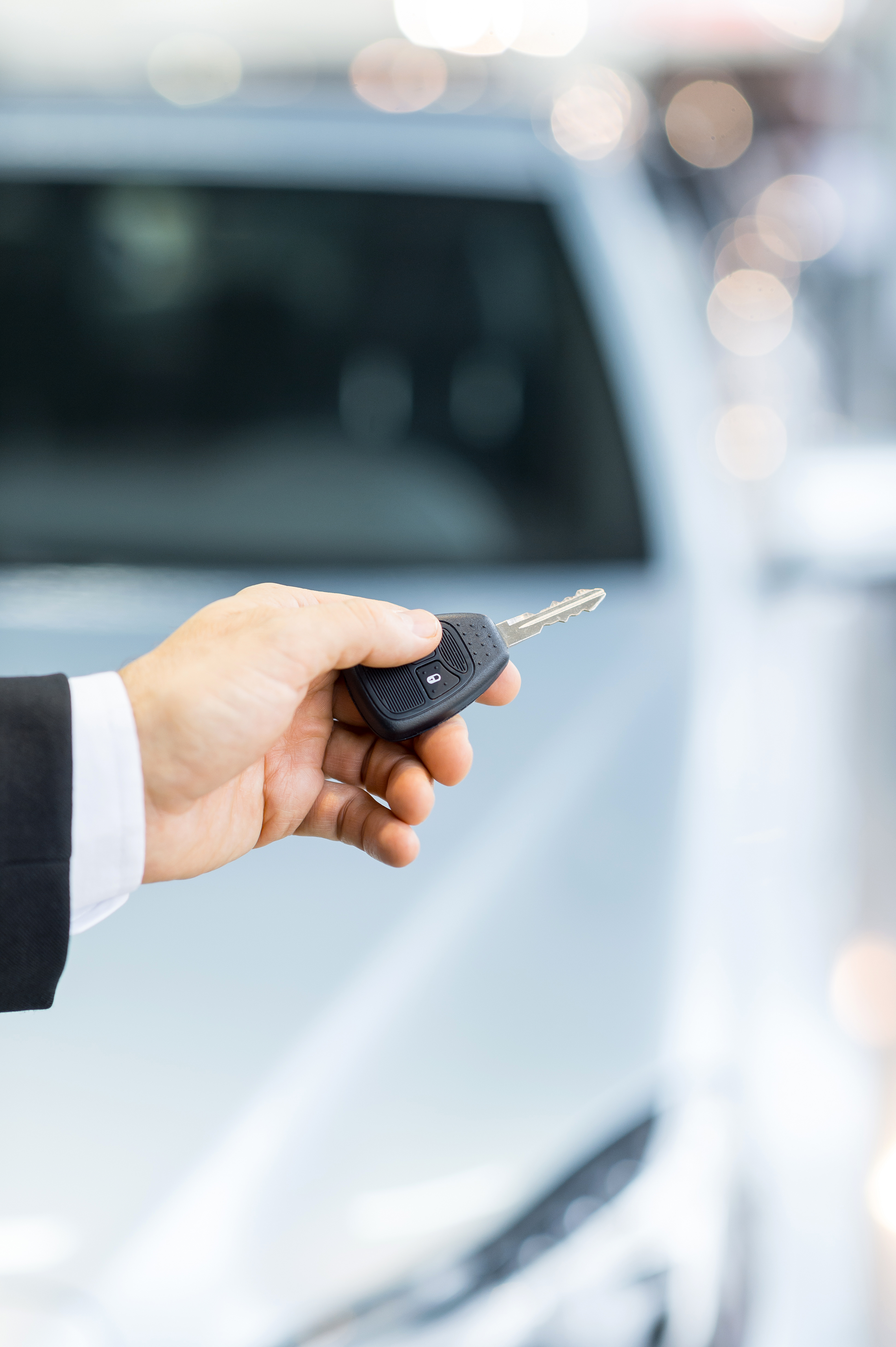 Drive carefully! Close up shoot of the hand holding car keys in front of a car